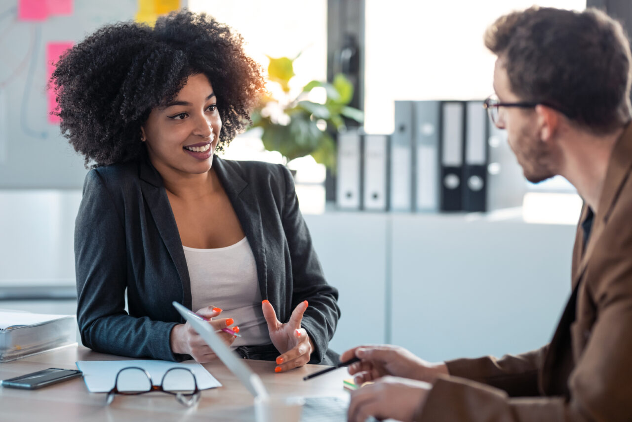 The woman on the left is a business mentor who is answering questions. The man on the right is an entrepreneur who seems to be asking about how to find a business mentor and what they do.