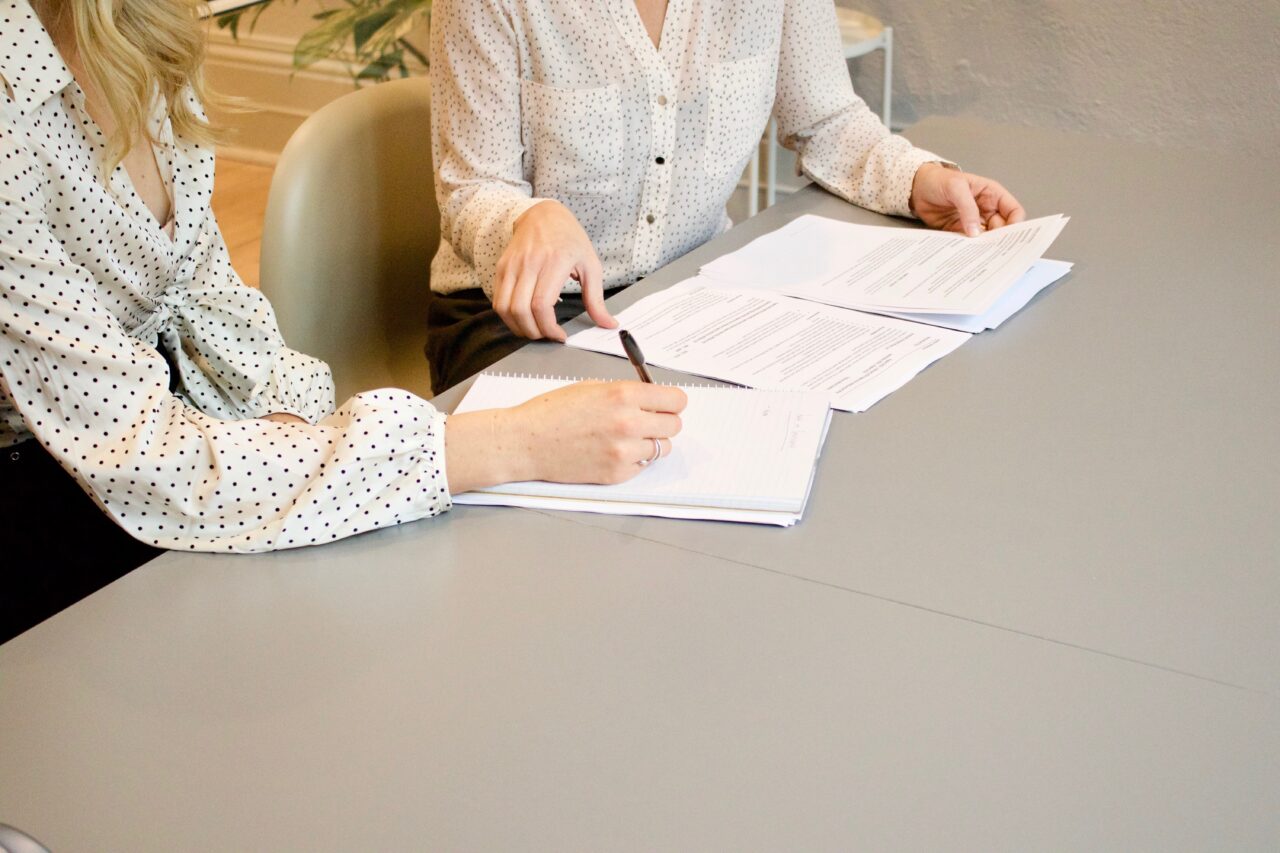 Two people are calculating the hidden cost of different recruitment models.